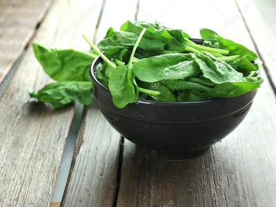 Fresh spinach in a wooden bowl on a wooden table