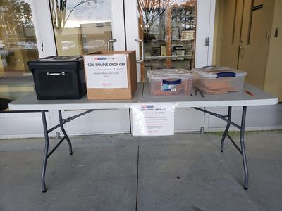 Plastic table with four boxes to indicate where soil sample kits can be picked up and returned
