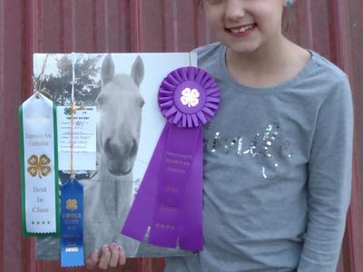 Girl holding horse photo with a purple ribbon and green ribbon reading "Best In Class."