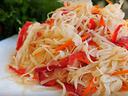 Shredded cabbage salad with sliced red bell pepper and carrot on a white plate