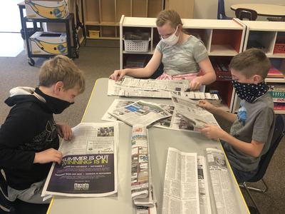 2 boys and a girl folding newspapers.