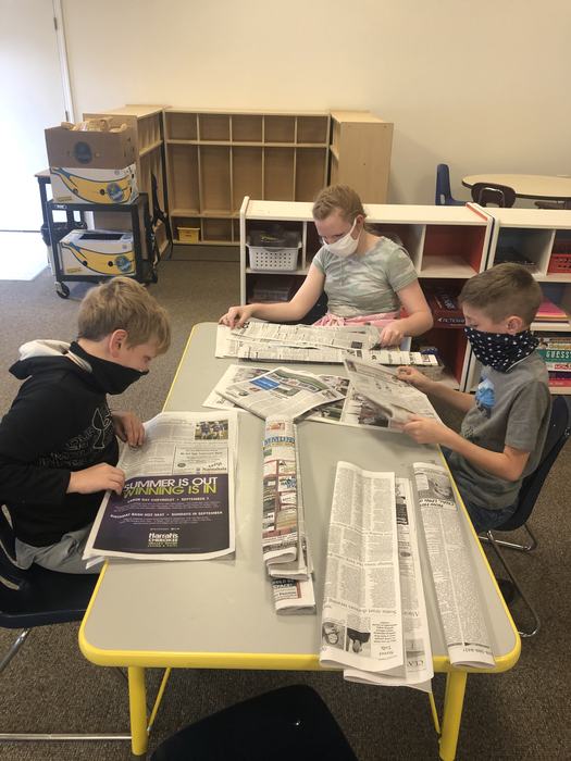 2 boys and a girl folding newspapers.