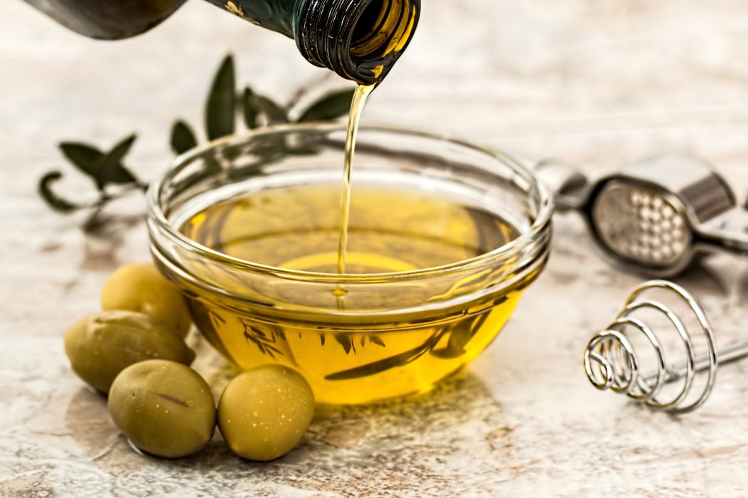 Yellow Olive Oil Being Poured into a Small Glass Bowl 
