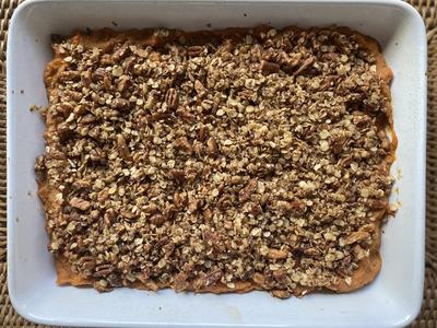 Baked sweet potato casserole topped with pecan and oat streusel in a white baking dish