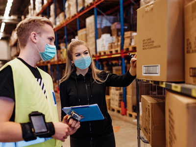 a man and a woman, wearing masks, in a warehouse