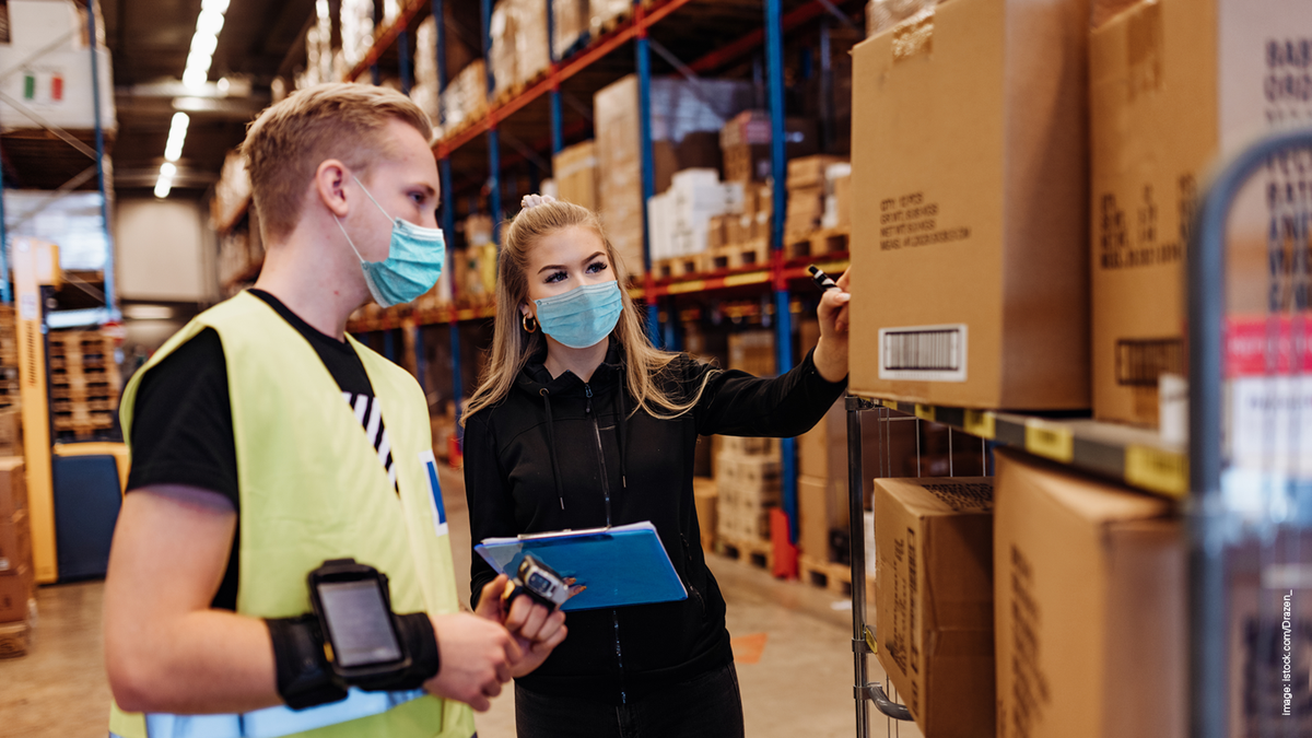 a man and a woman, wearing masks, in a warehouse