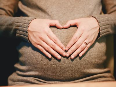 Hands forming a heart shape on a pregnant belly