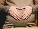 Hands forming a heart shape on a pregnant belly