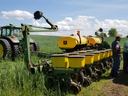 John Deere tractor towing MaxEmergePlus planter while workers load seed bags