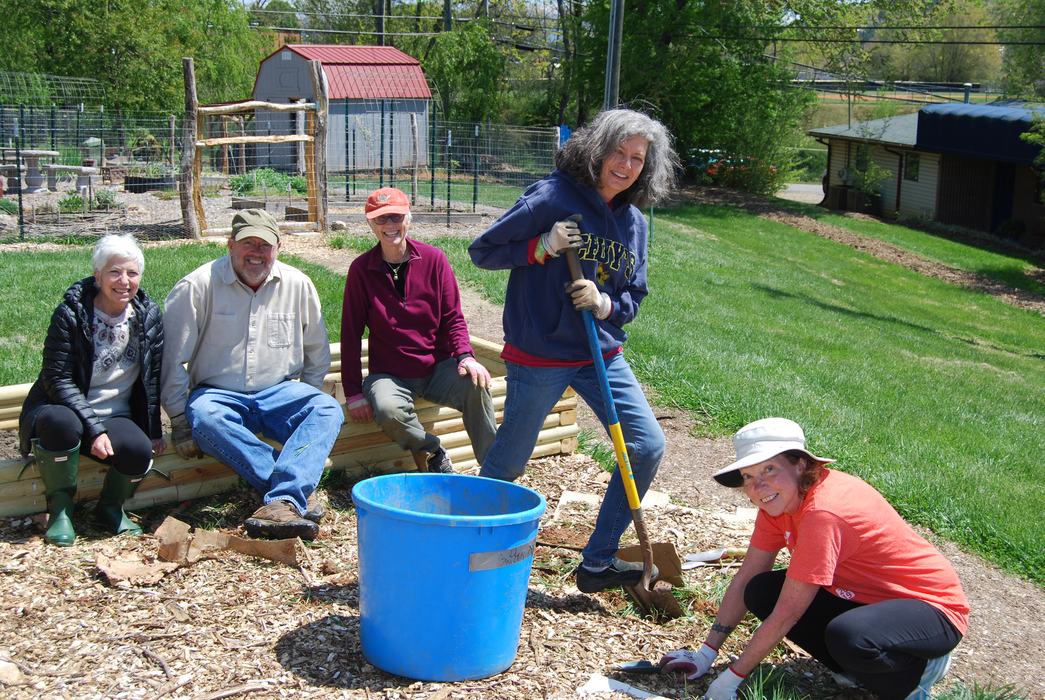 Gardener with a shovel and other gardeners looking on or helping
