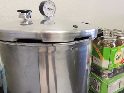 pressure canner and glass jars on a table.