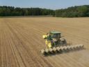 Green tractor towing a multi-row planter seeding a large plowed field