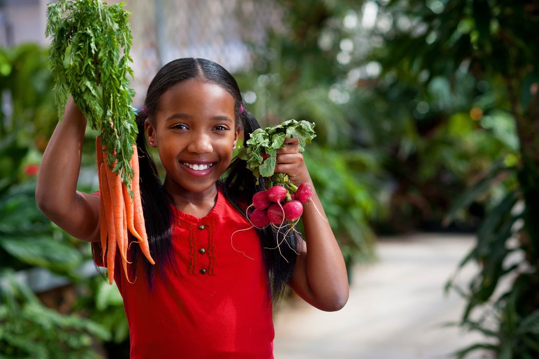 Girl holding carrots and radishes