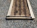 Raised wooden garden bed with three parallel drip irrigation tubes and gravel surrounding