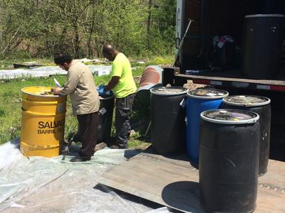 Two workers handling barrels beside a truck; yellow barrel labeled "SALVAGE"