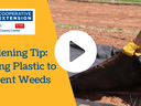 Person wearing gloves laying black plastic; text: Gardening Tip: Laying Plastic to Prevent Weeds