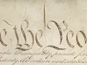 Handwritten calligraphy heading "We the People" on aged parchment document