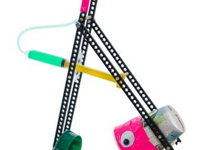 Tabletop DIY trebuchet of perforated metal strips with a syringe trigger and plastic cups