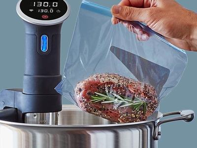 Silver Pot with Sous Vide Device and Hand Holding plastic bag with meat and herbs