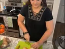 FCS agent holding knife and chopping onions. Vegetable stand in left of image with tomatoes, sweet potatoes, and other vegetables.