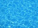 Swimming pool surface with sunlight reflections and rippling water