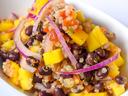 Bowl of mango, black bean and quinoa salad with sliced red onion