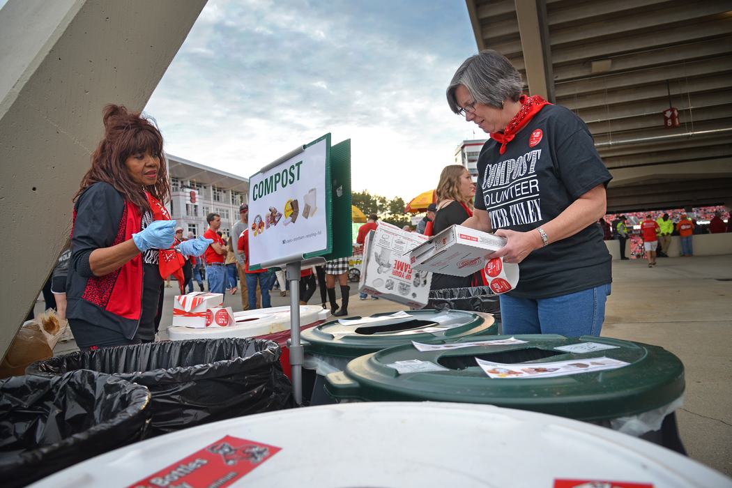 NC State University compost volunteer Lynn Odom puts pizza boxes in the proper composting bins during halftime of the Wolfpack football game against Clemson University in Raleigh, NC.