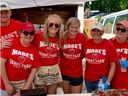 Six people in red "Mabe's Berry Farm" shirts selling boxes of strawberries at a stall; sign "STRAWBERRIES"
