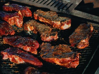 Image of steaks cooking on top of a grill