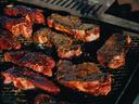 Image of steaks cooking on top of a grill