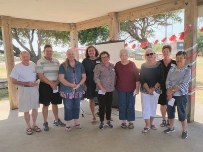Ten adults standing in a wooden pavilion at a park, facing the camera
