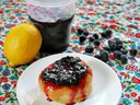 Lemon, jar of blueberry jam, and biscuit topped with blueberry jam on floral tablecloth