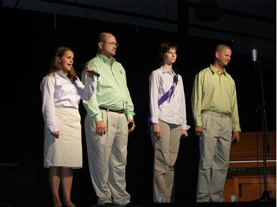 Four people singing on stage