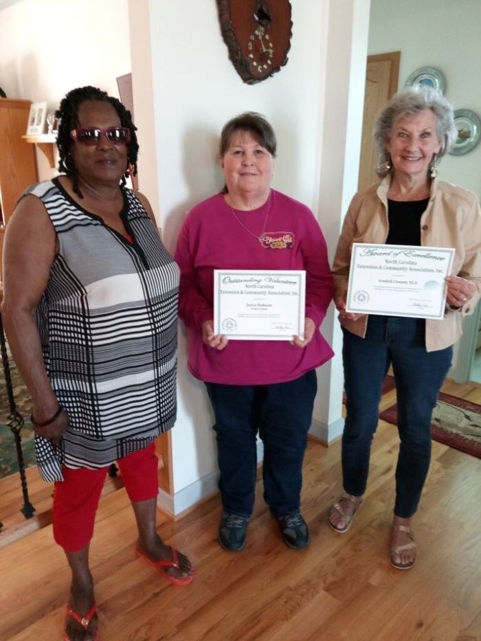 Three women, two holding awards