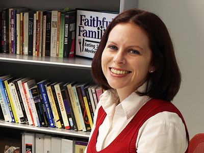 Woman smiling in front of bookshelf