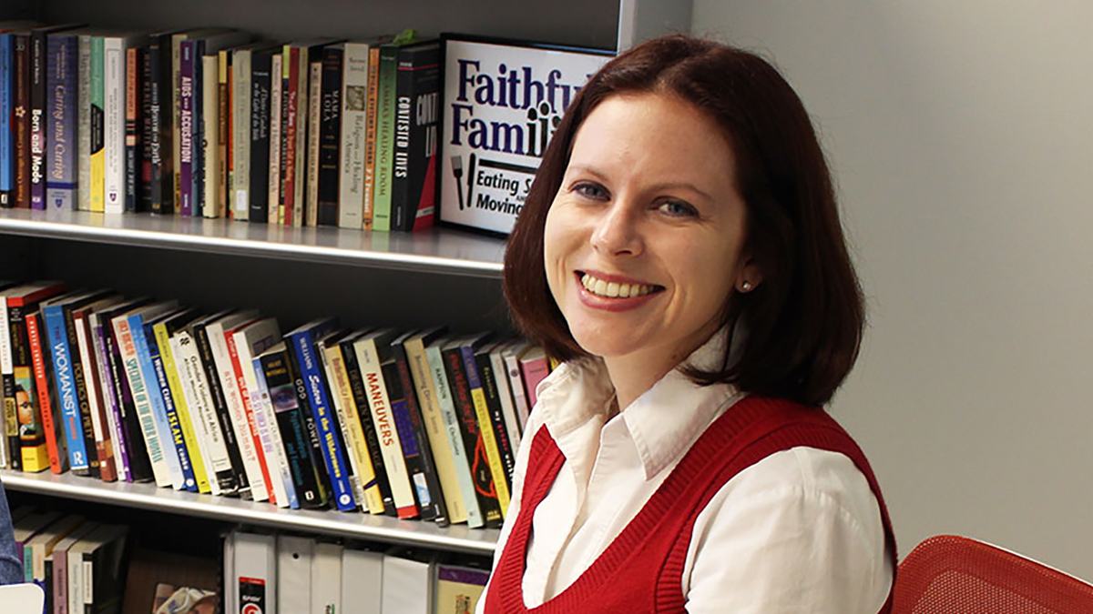 Woman smiling in front of bookshelf