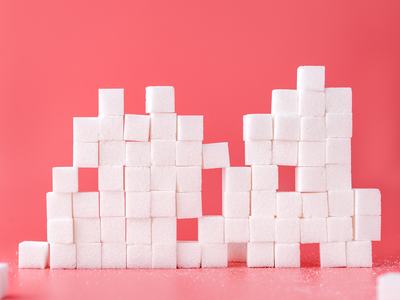 Sugar cubes stacked in front of pink background