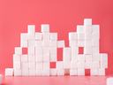 Sugar cubes stacked in front of pink background