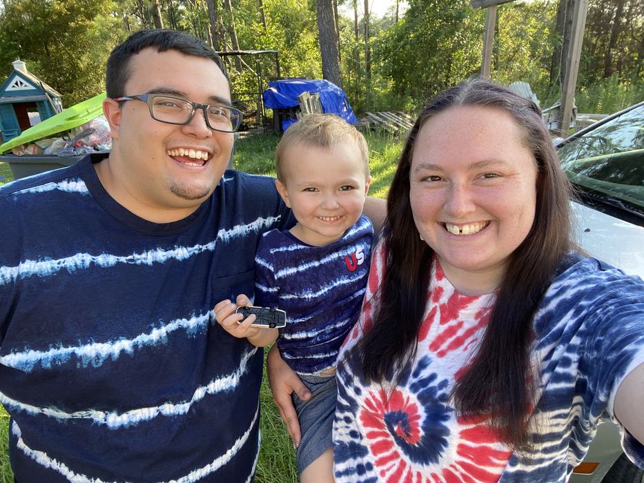 Angelique standing beside her partner and holding her son.