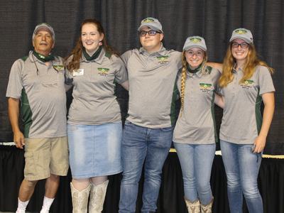 Five people in gray polo shirts and caps labeled 2021 NATIONALS RIFLE standing arm-in-arm