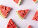 Triangular watermelon slices arranged on a white textured surface