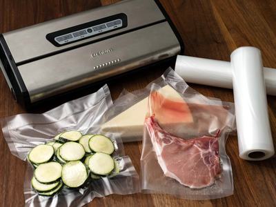 Vacuum_sealer_with_food_sealed_on_wooden_table_and_rolls_of_plastic_for_sealing