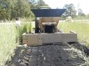A tractor spreads biochar in a field.