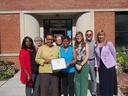 Group of eight people standing outside Durham County building (721) holding a certificate