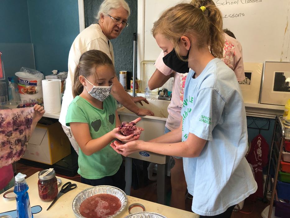Junior leader Emma Combs assists Rylie Bryant with her dyed cloth during Art Outside in July.