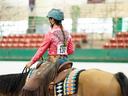 Equestrian rider wearing helmet and pink shirt (number 130) riding a saddled horse