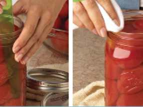 Hands inserting plastic tools into a jar of whole peeled tomatoes during canning.