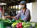 A farmers market in operation during Covid-19. Farmers behind their produce tables at a farmers market.