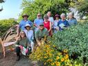 Group of gardeners posing by butterfly-shaped bench and yellow coneflowers
