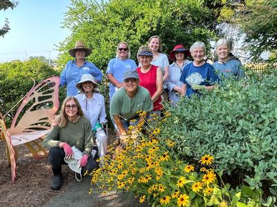 Group of gardeners posing by butterfly-shaped bench and yellow coneflowers